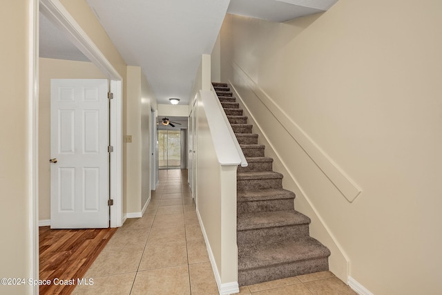 stairs with wood-type flooring and ceiling fan