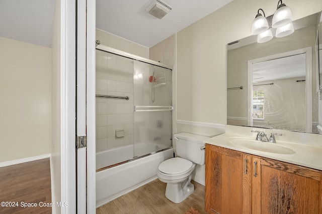 full bathroom with toilet, bath / shower combo with glass door, hardwood / wood-style flooring, and vanity