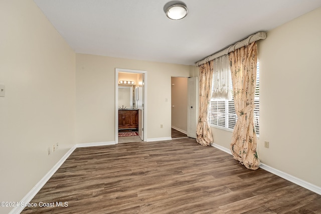 unfurnished bedroom with a closet, ensuite bath, and dark hardwood / wood-style flooring