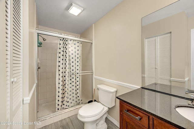 bathroom with vanity, hardwood / wood-style floors, toilet, and a shower with door