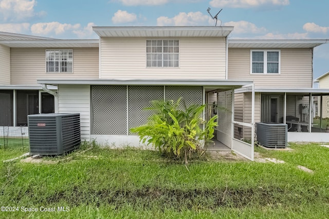 rear view of property featuring central AC, a lawn, and a sunroom