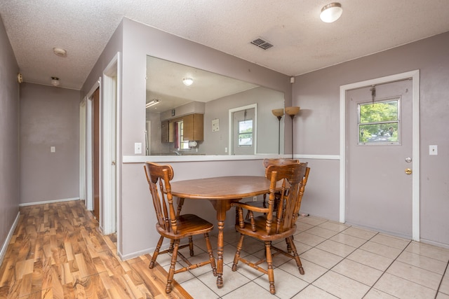 dining area with a textured ceiling and light hardwood / wood-style floors