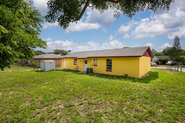 rear view of house featuring central air condition unit and a lawn