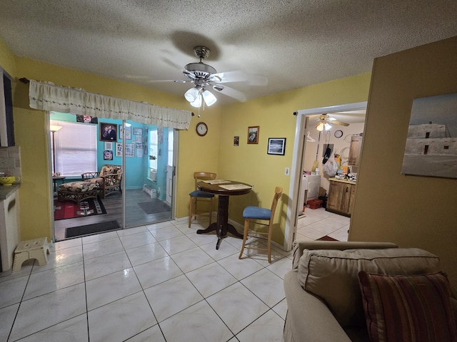 tiled dining space with a textured ceiling and ceiling fan