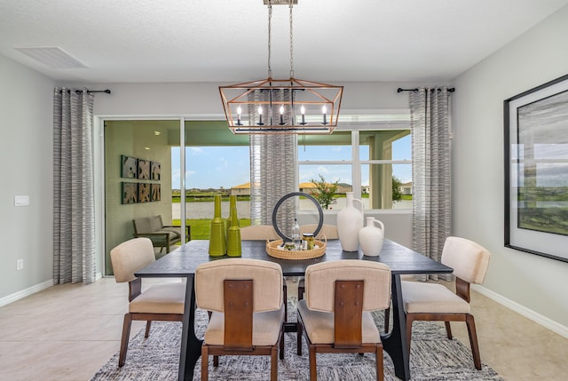 dining space with light tile patterned floors, a notable chandelier, and a textured ceiling