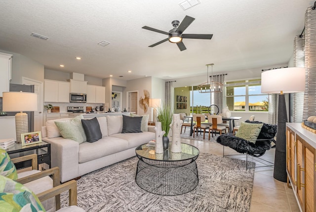 living room featuring ceiling fan, a textured ceiling, and light tile patterned flooring