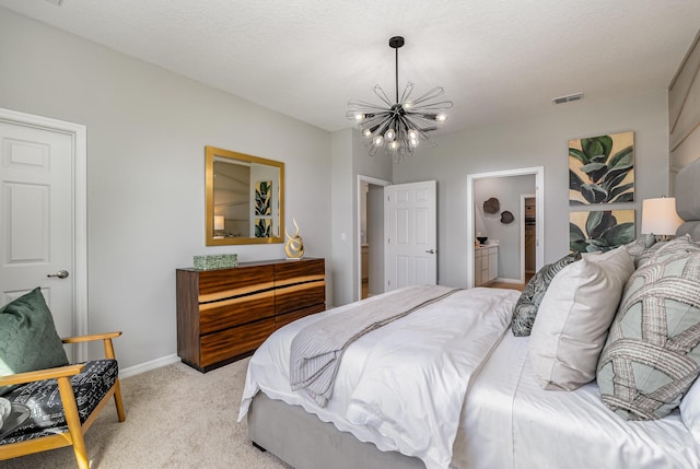 bedroom with ensuite bathroom, light colored carpet, a notable chandelier, and a textured ceiling