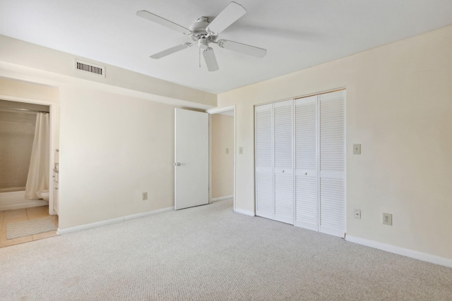 unfurnished bedroom featuring ceiling fan, a closet, ensuite bathroom, and light carpet