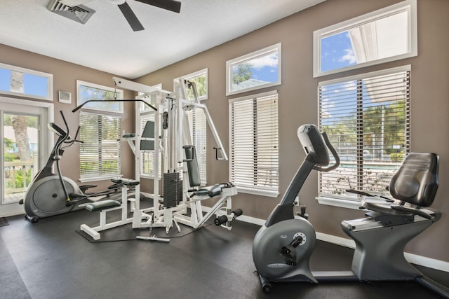 exercise room with ceiling fan and a textured ceiling