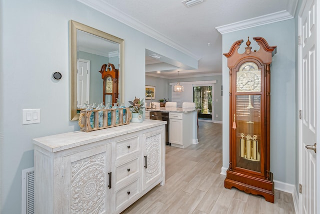 entryway with ornamental molding and light hardwood / wood-style floors