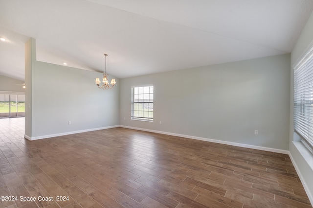 unfurnished room featuring dark wood-type flooring, a chandelier, and vaulted ceiling