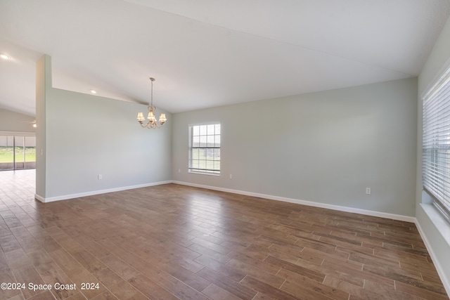 spare room featuring dark wood-style floors, vaulted ceiling, and baseboards