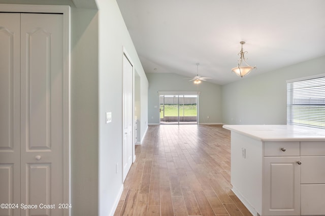 hallway featuring light wood-type flooring, vaulted ceiling, and baseboards