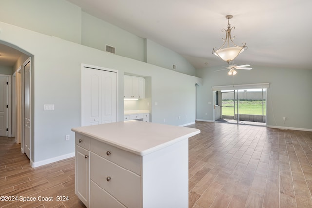 kitchen featuring light wood-type flooring, a kitchen island, ceiling fan, vaulted ceiling, and white cabinets