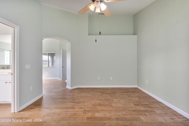 empty room featuring light hardwood / wood-style flooring, a high ceiling, and ceiling fan