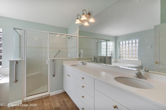 full bath with double vanity, a stall shower, a sink, wood finished floors, and a bath