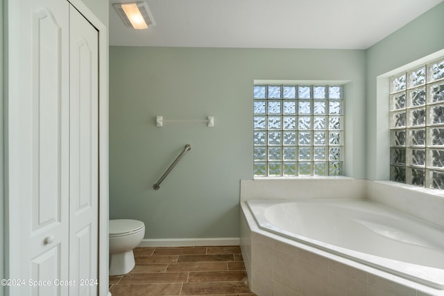 full bathroom featuring baseboards, visible vents, toilet, wood tiled floor, and a bath