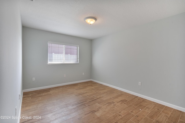 spare room featuring a textured ceiling and light hardwood / wood-style floors