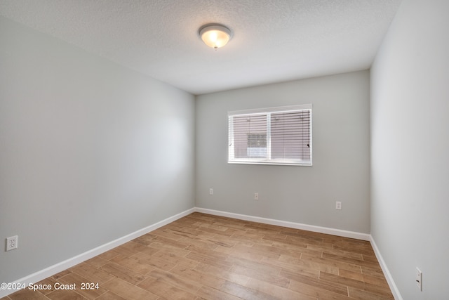 unfurnished room with a textured ceiling and light hardwood / wood-style floors