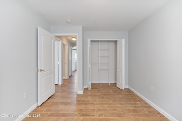 unfurnished bedroom featuring a closet, light wood-type flooring, and baseboards