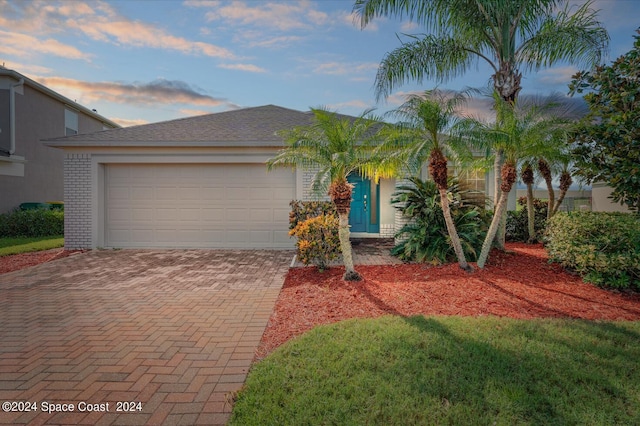 view of front of house featuring brick siding, decorative driveway, and an attached garage