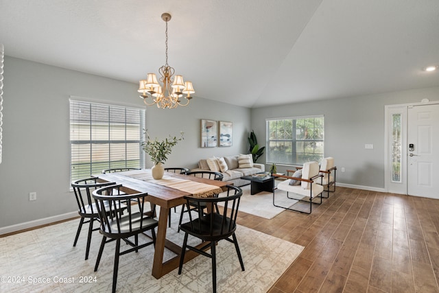 dining space with hardwood / wood-style flooring, lofted ceiling, plenty of natural light, and a chandelier