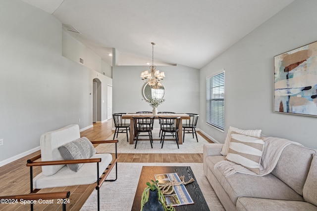 living room with an inviting chandelier, light hardwood / wood-style floors, and vaulted ceiling