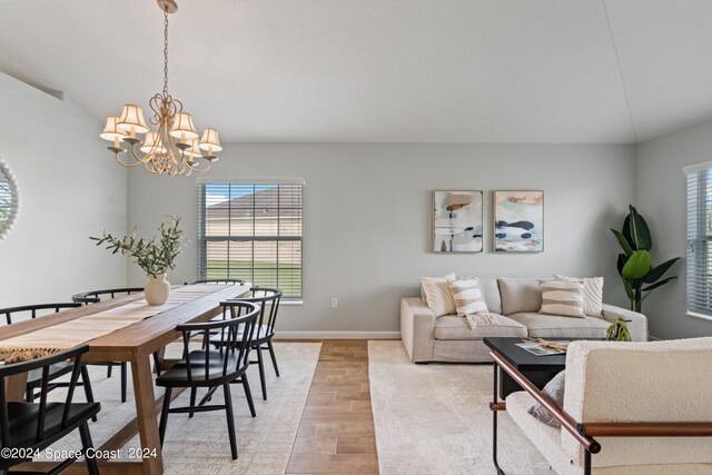 living room with lofted ceiling, a notable chandelier, and light wood-type flooring