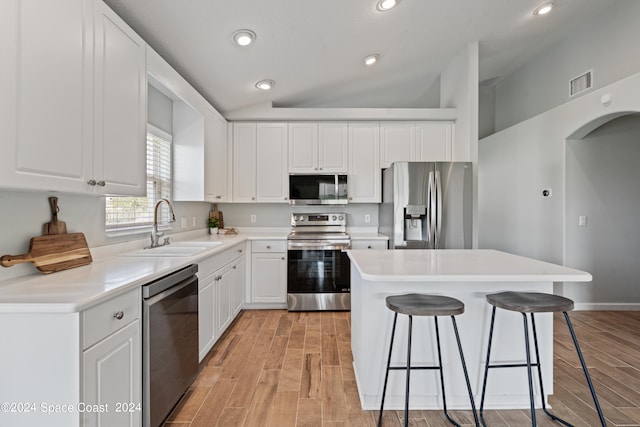 kitchen with white cabinetry, a kitchen island, sink, appliances with stainless steel finishes, and lofted ceiling