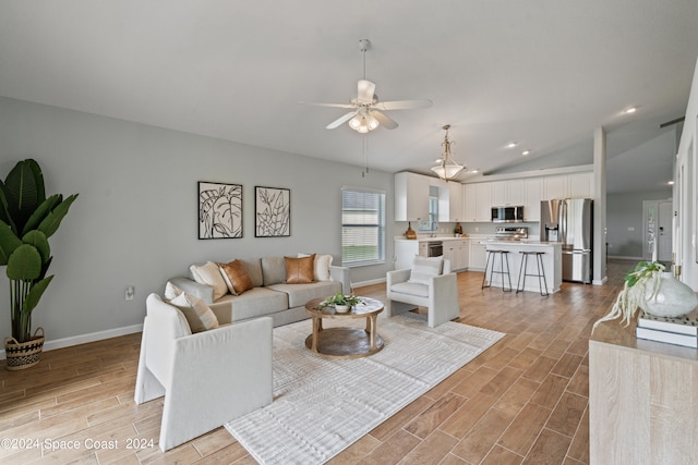 living room with light wood-type flooring, vaulted ceiling, sink, and ceiling fan