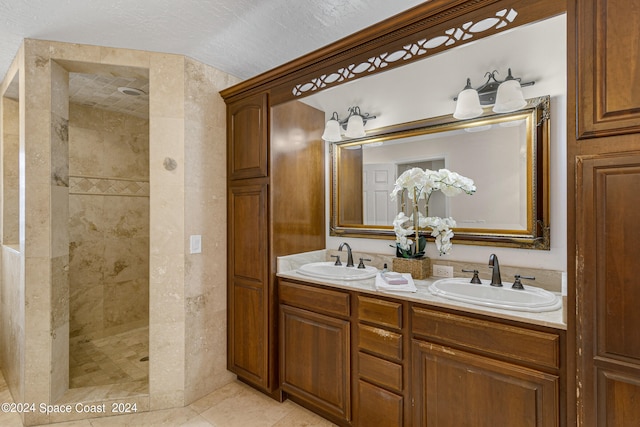 bathroom with vanity, a textured ceiling, tiled shower, and tile patterned flooring