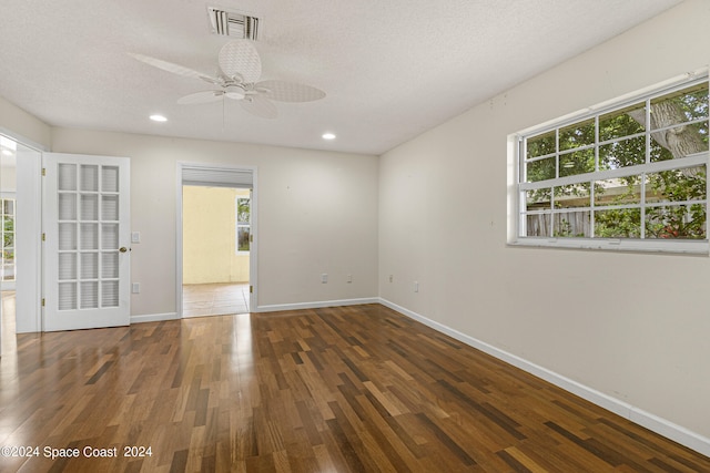 unfurnished room with dark wood-type flooring, ceiling fan, a textured ceiling, and a healthy amount of sunlight