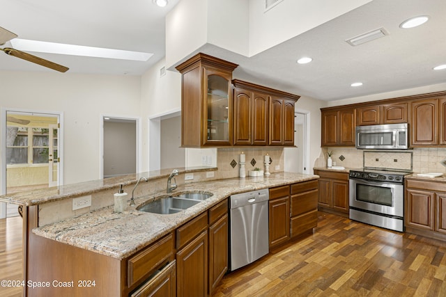 kitchen with tasteful backsplash, dark hardwood / wood-style flooring, kitchen peninsula, sink, and appliances with stainless steel finishes