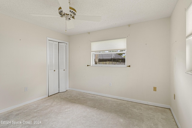 carpeted empty room with ceiling fan and a textured ceiling