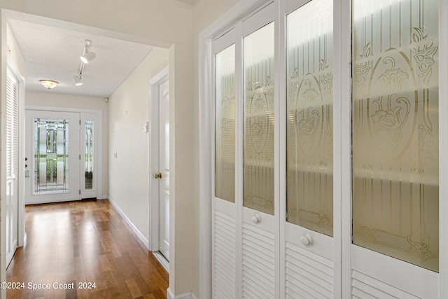 hallway featuring track lighting, a textured ceiling, and hardwood / wood-style floors