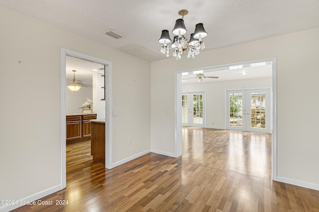 interior space featuring ceiling fan with notable chandelier, french doors, a textured ceiling, and hardwood / wood-style floors