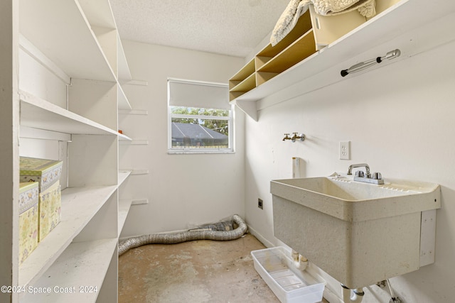 laundry area featuring hookup for a washing machine, sink, hookup for an electric dryer, and a textured ceiling