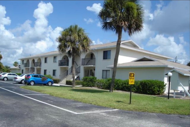 view of front facade with a balcony and a front lawn