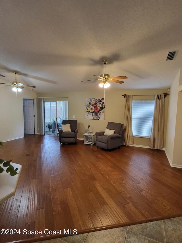 unfurnished living room featuring a textured ceiling, dark hardwood / wood-style floors, and ceiling fan