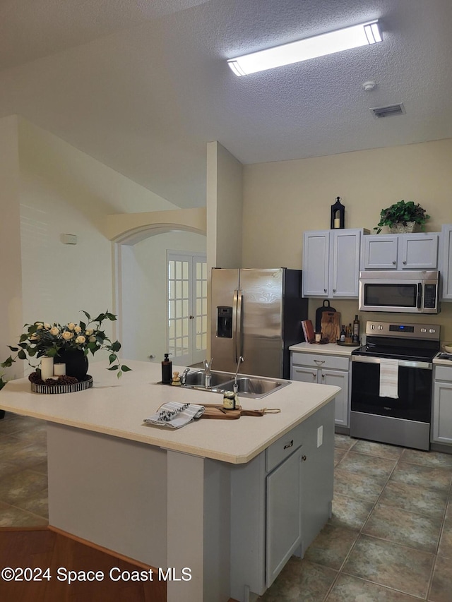 kitchen with sink, a center island, stainless steel appliances, and a textured ceiling