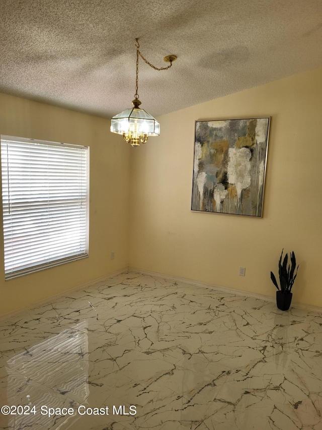 empty room with a chandelier, vaulted ceiling, and a textured ceiling