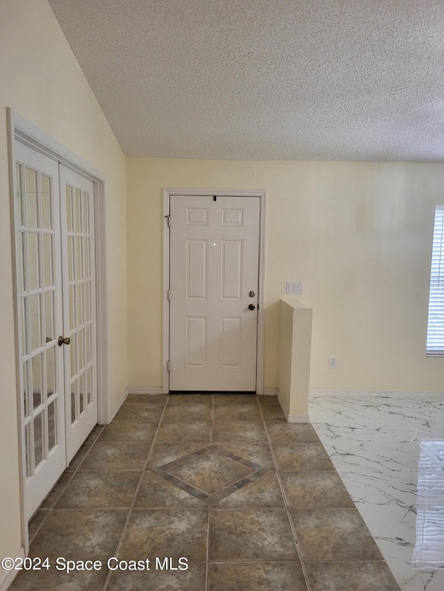 doorway with lofted ceiling and a textured ceiling