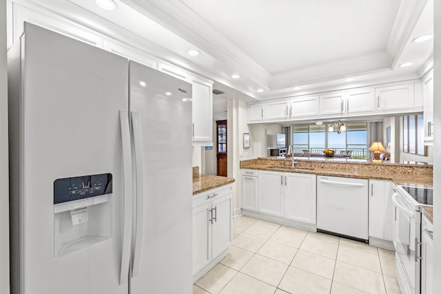 kitchen with stone counters, white appliances, sink, white cabinetry, and a raised ceiling