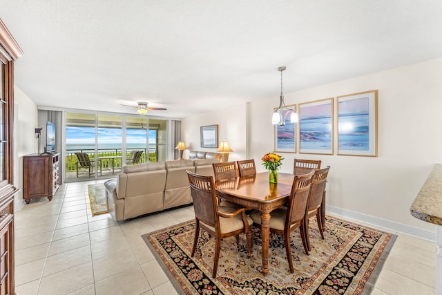 tiled dining room with a wall of windows and ceiling fan with notable chandelier