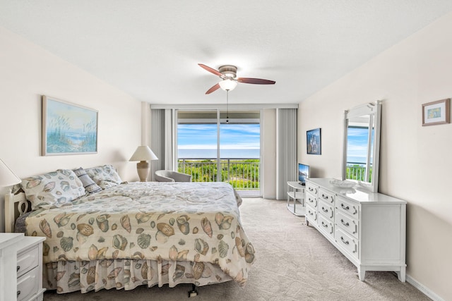 carpeted bedroom with access to outside, ceiling fan, multiple windows, and floor to ceiling windows