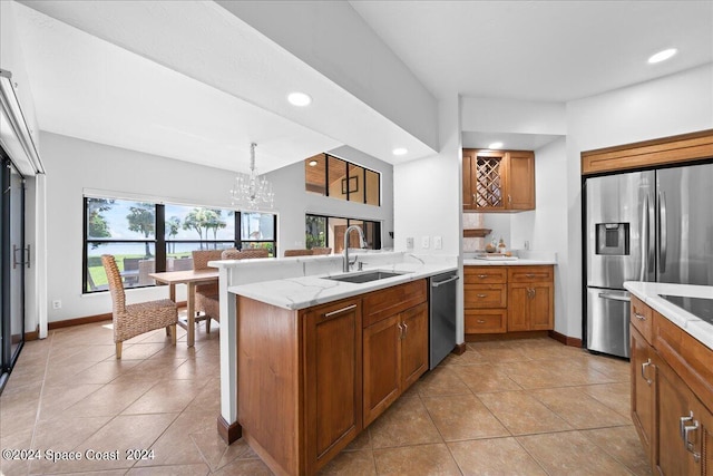 kitchen with an inviting chandelier, decorative light fixtures, kitchen peninsula, sink, and stainless steel appliances