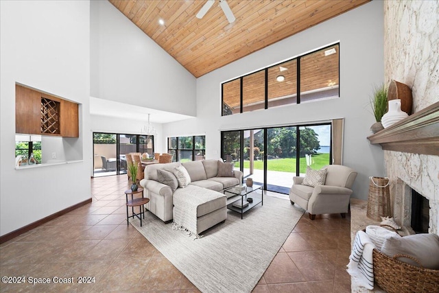 living room with wood ceiling, ceiling fan with notable chandelier, a stone fireplace, and high vaulted ceiling