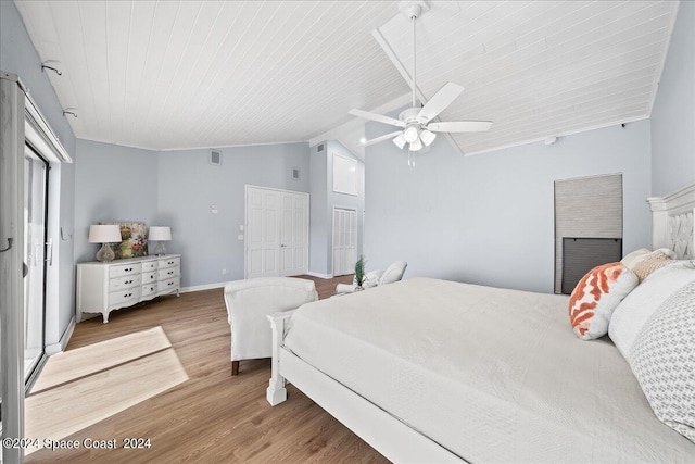 bedroom featuring two closets, ceiling fan, hardwood / wood-style flooring, and vaulted ceiling