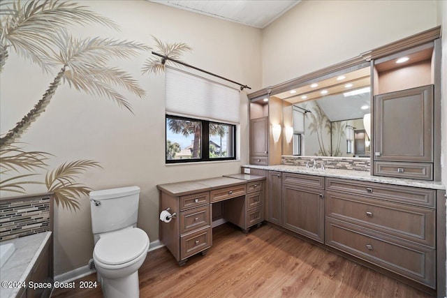 bathroom with backsplash, hardwood / wood-style floors, toilet, a washtub, and vanity