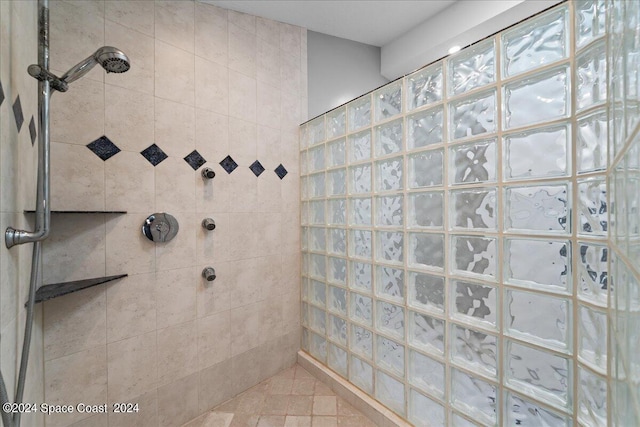 bathroom with tiled shower and tile patterned flooring